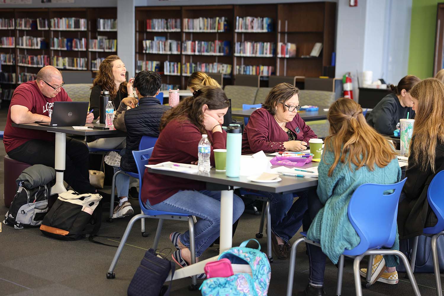 Students and teachers studying at tables in a library